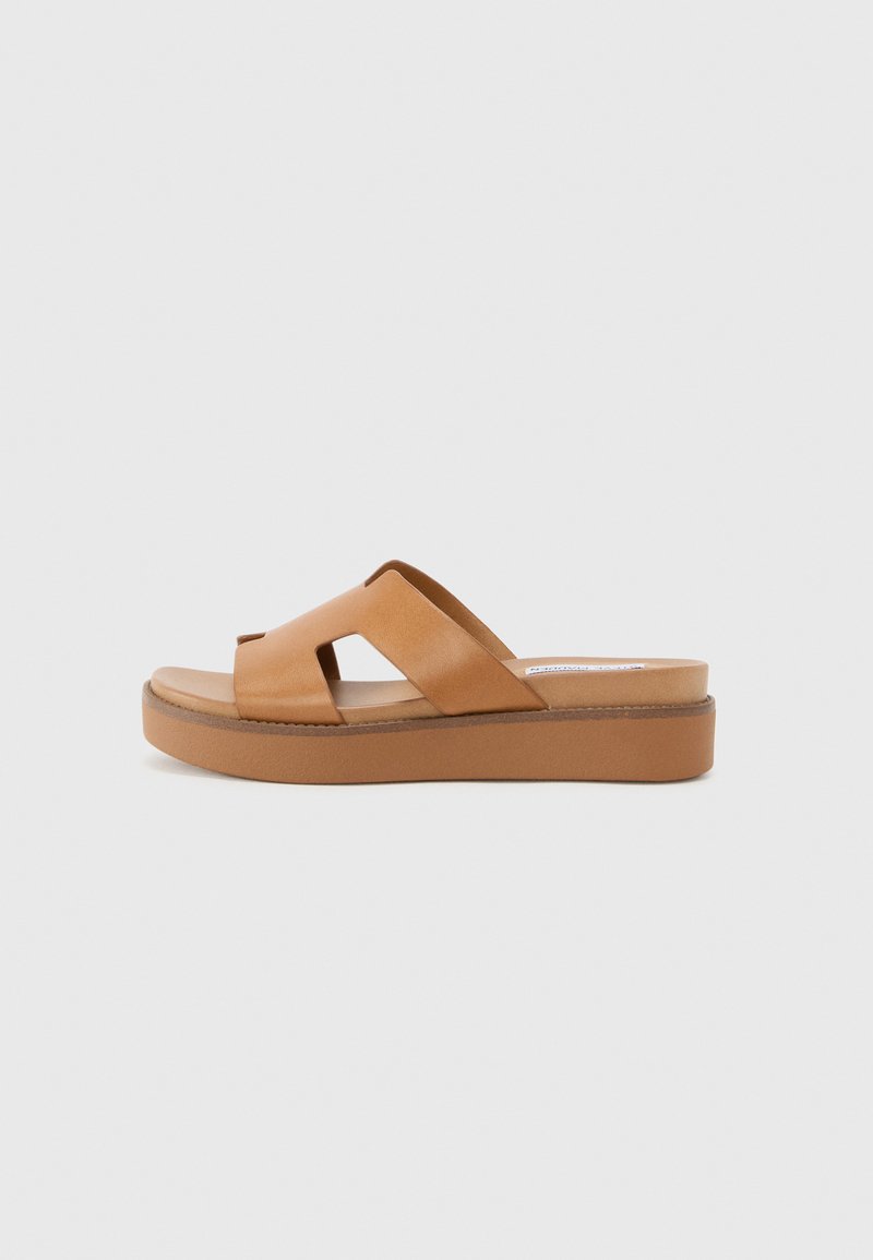 Helle Ledersandalen mit zwei sich überkreuzenden Riemen und einer dicken Plattformsohle. Sanfte Textur mit subtiler Nahtdetails entlang der Kanten.