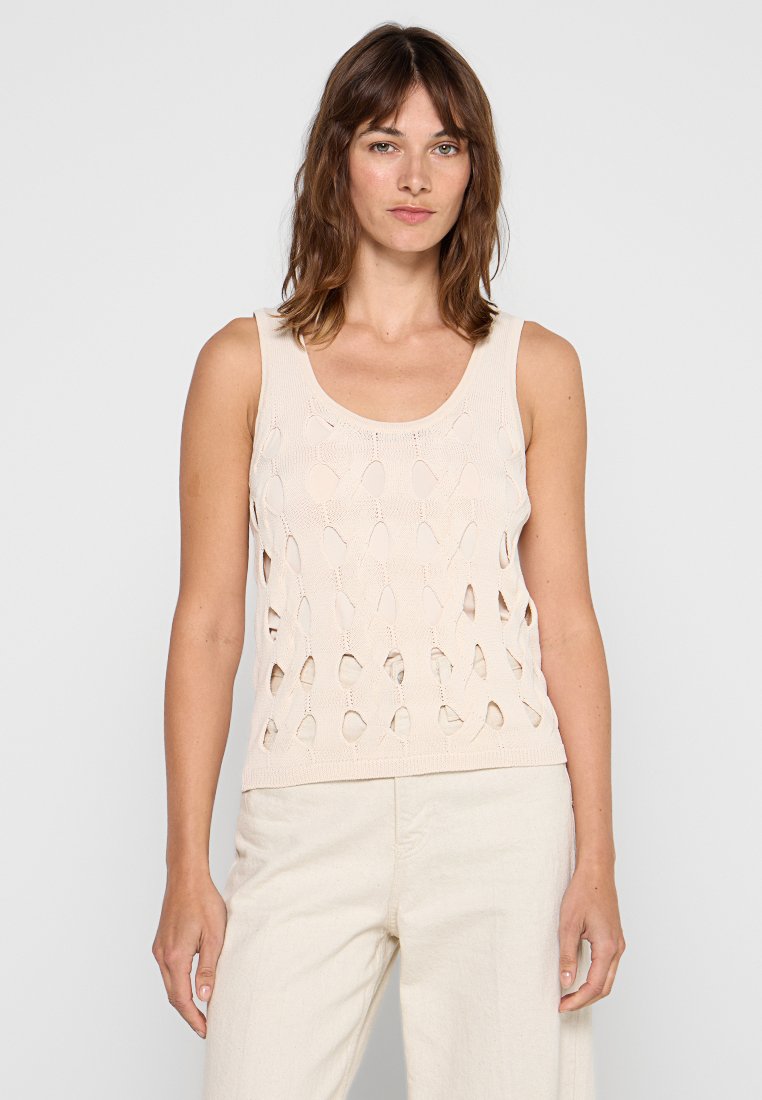 Beige gestricktes Tanktop mit runder Ausschnitt und durchbrochenen ovalen Mustern auf der Vorderseite, kombiniert mit hellen Hosen.
