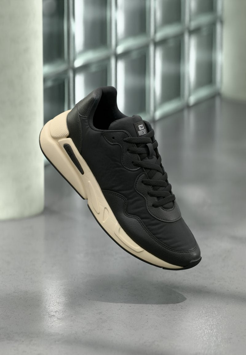 Schwarzer Sportschuh mit strukturiertem Lederobermaterial, dicker cremefarbener Sohle, abgerundetem Zehenbereich und dezentem Logodetail auf der Zunge.