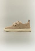 Beiger Wildleder-Sneaker mit doppelten Klettverschlüssen, perforierten dekorativen Mustern und einer cremefarbenen Gummisohle, seitlich auf hellem Hintergrund gezeigt.
