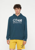 Junger Mann mit lockigem Haar, der einen blauen O'Neill Hoodie und gelbe Shorts mit dem Text "The Future Surf Society" am linken Bein trägt.