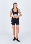 Schwarzer Sport-BH mit mehrfarbigen Akzenten, kombiniert mit schwarzen Radshorts mit einem bunten Seitenpanel-Design. Schwarze Sportschuhe.