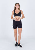 Schwarzer Sport-BH mit mehrfarbigen Akzenten, kombiniert mit schwarzen Radshorts mit einem bunten Seitenpanel-Design. Schwarze Sportschuhe.