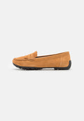 Beige Wildleder-Loafer mit runder Zehenform, dekorativem Riemen und schwarzem Gummisohle, die über rutschfeste Noppen verfügt. Glatte Textur.