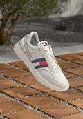 Weiße Sneakers mit Mesh- und Wildlederelementen, die ein rot-weiß-blau gestreiftes Logo an der Seite aufweisen. Strukturierten Gummisohle, Schnürdesign.