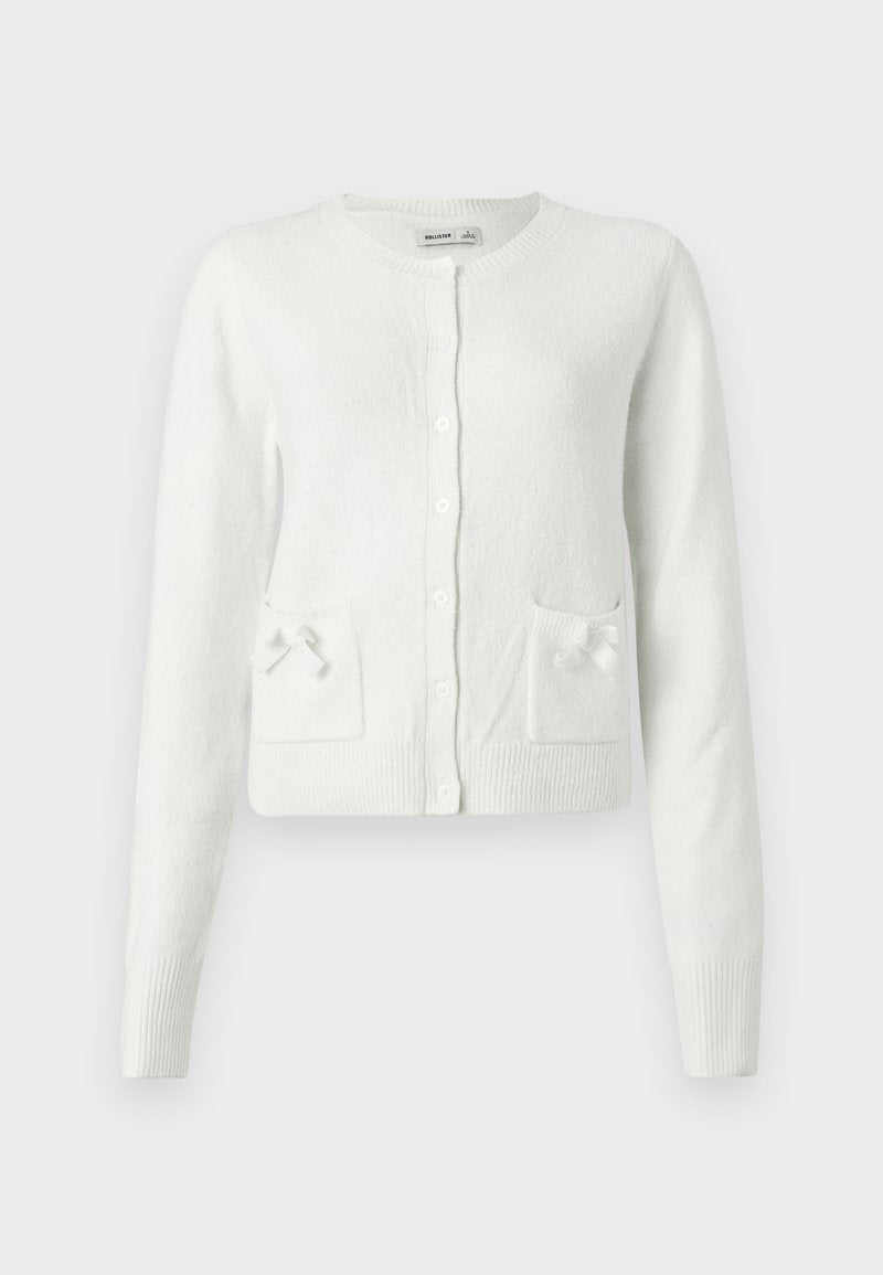 Weißer, gestrickter Cardigan mit langen Ärmeln, rundem Ausschnitt, Knopfverschluss und zwei Taschen, die mit kleinen Schleifen verziert sind. Weiches, strukturiertes Material.