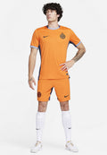 Orangenes Nike Fußballtrikot mit grauen Akzenten, ausgestattet mit einem Rundhalsausschnitt, Logo auf der Brust und passenden Shorts. Weiße Socken und Sneaker runden den Look ab.