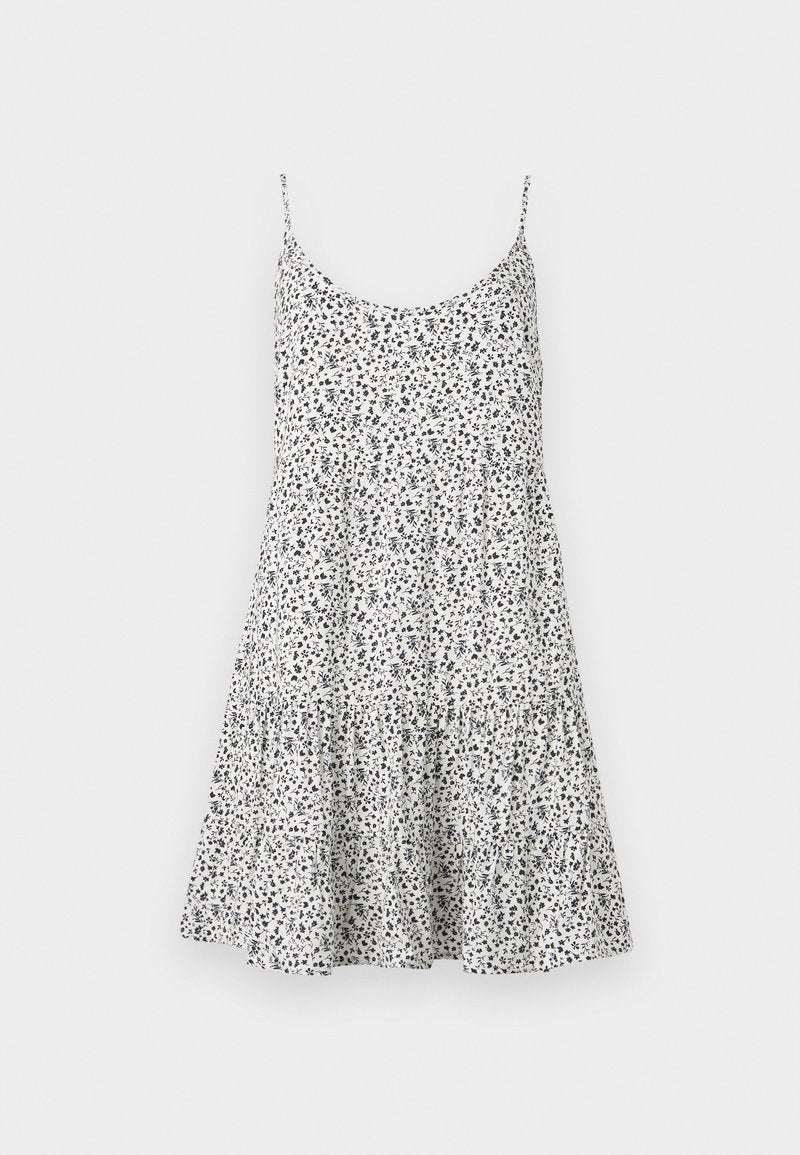 Weißes ärmelloses Sommerkleid mit dünnen Trägern, kleinem schwarzem Blumenmuster und einem Rock mit Stufen.