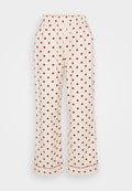 Cremefarbene Schlafanzughose mit roten Polka-Dots, ausgestattet mit einem elastischen Bund und seitlichen Taschen. Der Stoff ist weich und hat eine glatte Textur.