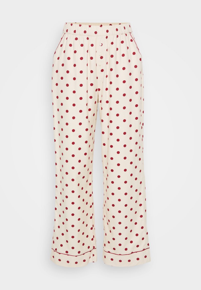 Cremefarbene Schlafanzughose mit roten Polka-Dots, ausgestattet mit einem elastischen Bund und seitlichen Taschen. Der Stoff ist weich und hat eine glatte Textur.