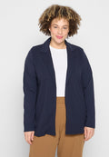 Marineblauer langer Blazer mit weicher Textur, offenem Frontdesign und Reverskragen, getragen über einem weißen Oberteil und braunen Hosen.