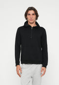 Schwarzer Kapuzenpullover mit Reißverschluss aus weichem Stoff und Kängurutasche. Mit Kapuze sowie gerippten Bündchen und Saum. Modell trägt graue Jogginghosen.