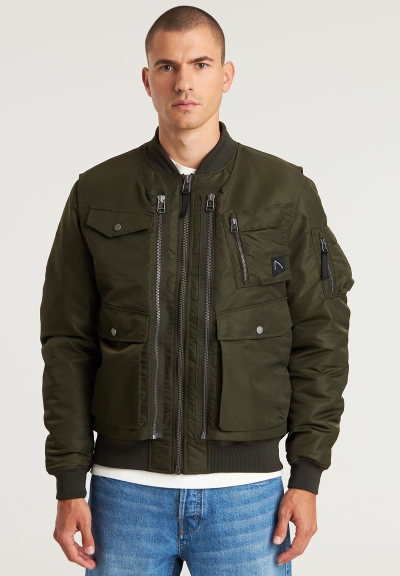 Olivgrüne Bomberjacke mit Reißverschlusstaschen, gerippten Bündchen und Saum. Hergestellt aus glattem, strapazierfähigem Stoff mit einer strukturierten Silhouette.