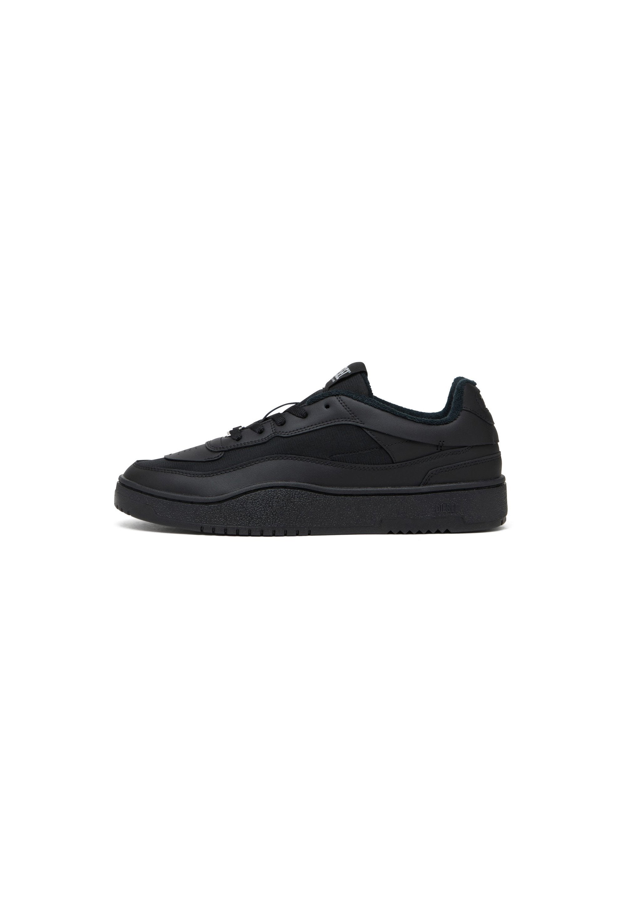 Schwarzer Sneaker aus glattem Leder und Textil, mit einer dicken Sohle, abgerundetem Zehenbereich und kontrastierenden Texturakzenten.