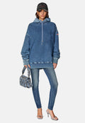 Oversized Denim-Hoodie mit Kordelzug, kombiniert mit eng anliegenden Jeans, einer gesteppten blauen Handtasche und transparenten Sandalen mit Absatz. Baseballkappe inklusive.