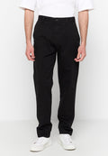 Schwarze gerade geschnittene Hosen mit einem Frontknopfverschluss, Gürtelschlaufen und Seitentaschen, aus glattem Baumwollstoff. Kombiniert mit weißen Sneakern.