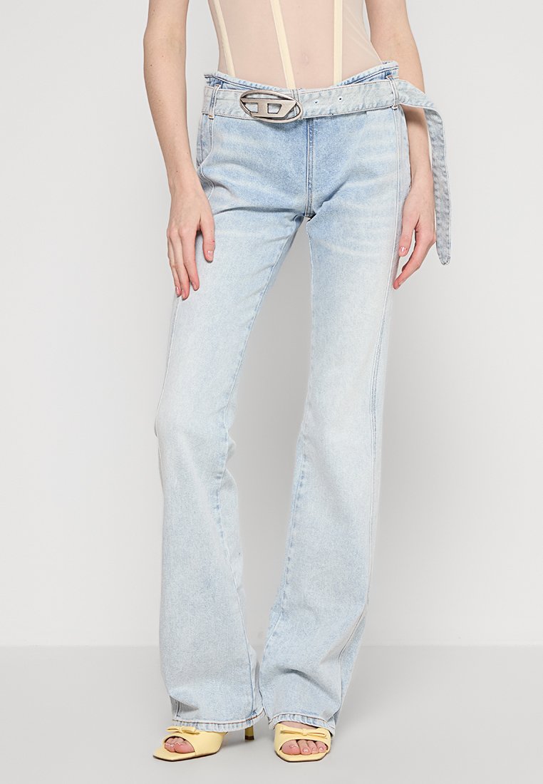Helle blaue Jeans im Bootcut-Stil mit breitem Bund und einem kontrastierenden hellblauen Gürtel. Mit einer silbernen Schnalle und leichtem Used-Look.