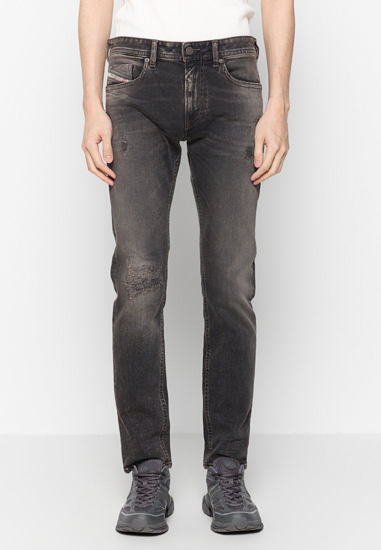 Schwarze Jeans aus Denim mit einem distressed Design, das sanfte Ausbleichungen und ausgefranste Knie-Details zeigt. Fünf-Taschen-Stil und ein Knopfverschluss.