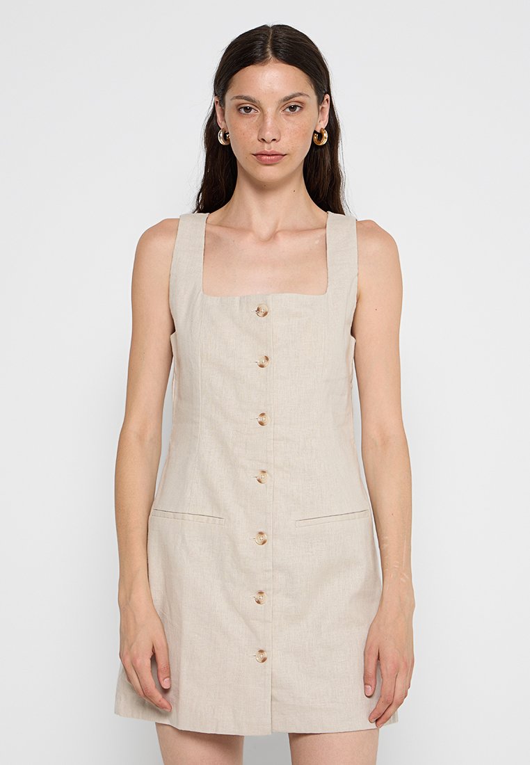 Beiges Leinenkleid mit quadratischem Ausschnitt, vorderen Knöpfen und zwei Seitentaschen. Ärmelloses Design und knielanger Schnitt. Lässiger Stil.
