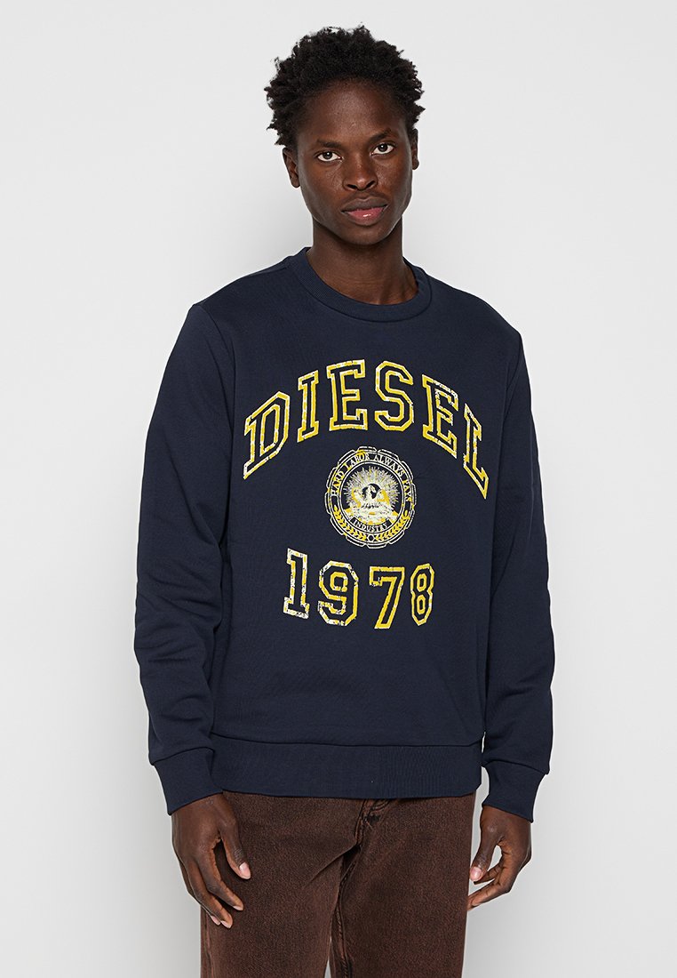 Marineblaues Sweatshirt mit gerippten Bündchen und Saum, das ein großes gelbes "DIESEL"-Logo und eine Grafik von 1978 in der Mitte zeigt. Weicher Stoff.