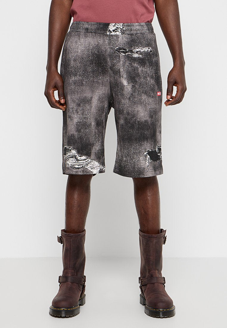 Schwarz-graue Denim-Shorts mit distressed Textur, die Risse und ein rotes Etikett aufweisen. Kombiniert mit dunkelbraunen Stiefeln. Lässiges Design.