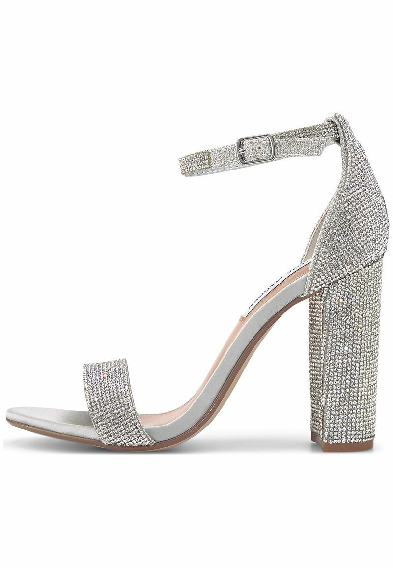 Silberne High Heel Sandalen mit einem klobigen Blockabsatz, einem Knöchelriemen mit Schnalle und Schmucksteinen auf den Riemen.