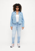 Helle blaue Jeansjacke mit zwei Fronttaschen, Knopfverschluss und darunter einem weißen Oberteil. Helle blaue Skinny-Jeans und sportliche Sneakers.