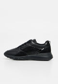Schwarzer Sneaker mit niedrigem Schaft, gemischten Texturen, Schnürung vorne und dicker Sohle, von der Seite auf weißem Hintergrund gezeigt.