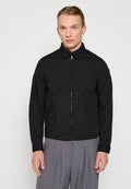 Schwarze Zip-Jacke mit spitzem Kragen, seitlichen Taschen und glatter Oberfläche. Besitzt einen geraden Schnitt und ein minimalistisch gestaltetes Design.