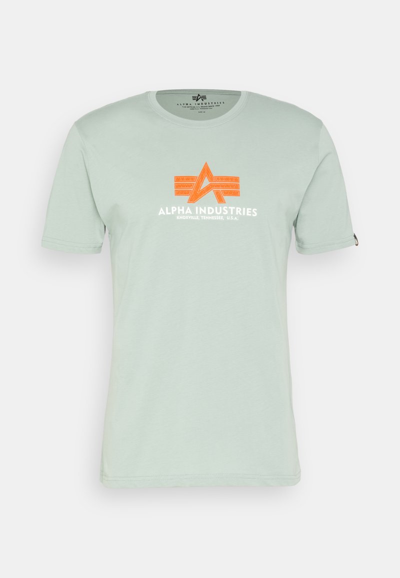 Hellgrünes T-Shirt mit kurzen Ärmeln, das ein oranges "Alpha Industries"-Logo und Designelemente auf der Vorderseite zeigt. Weiches Baumwollmaterial.