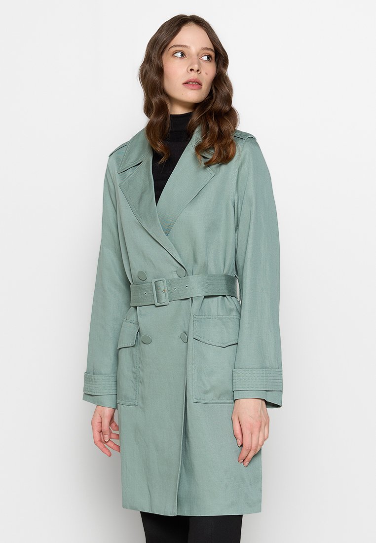 Helle grüne Trenchcoat aus glattem Stoff, mit doppelter Knopfleiste, tailliertem Gürtel, großen Fronttaschen und maßgeschneiderten Manschetten.