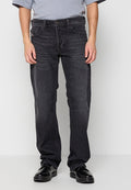Schwarze Denim-Jeans mit geradem Bein, fünf Taschen, dezenten Waschungen und einem Knopfverschluss. Getragen mit schwarzen Schuhen und einem grauen Oberteil.