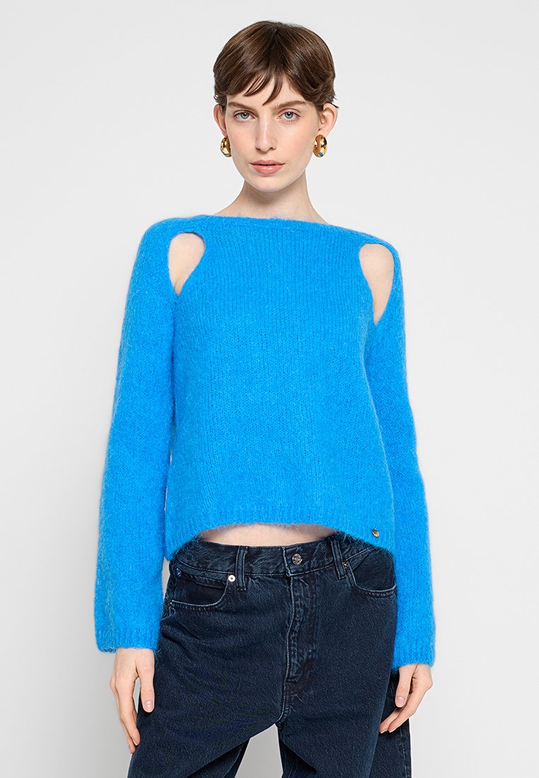 Blauer, verkürzter Pullover aus flauschigem Material mit ausgeschnittenen Schultern, langen Ärmeln und einem lässigen Schnitt. Auffälliges goldfarbenes Hardware-Detail.