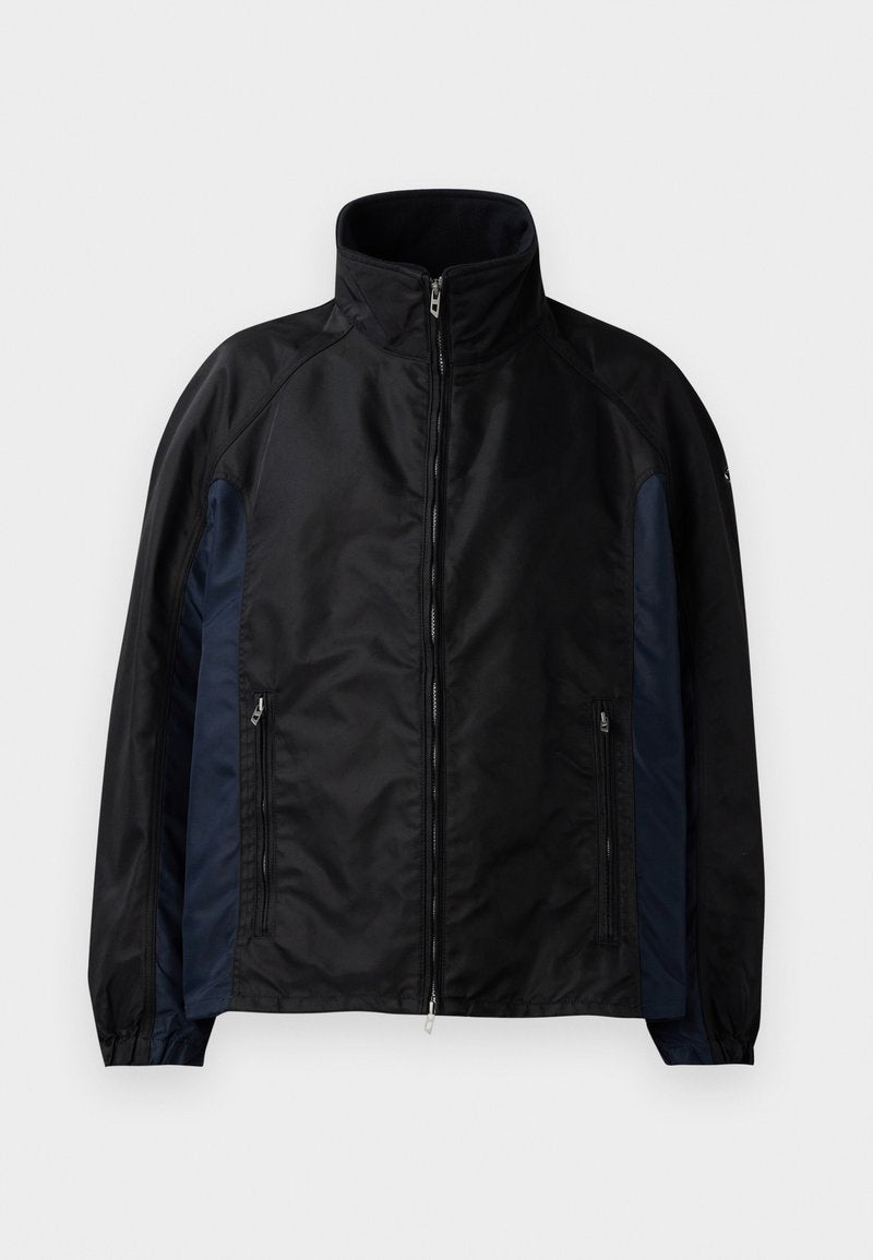 Schwarze und marineblaue Windbreaker-Jacke mit hohem Kragen, Reißverschluss vorne und seitlichen Taschen, elastischen Bündchen und einer glatten Textur.