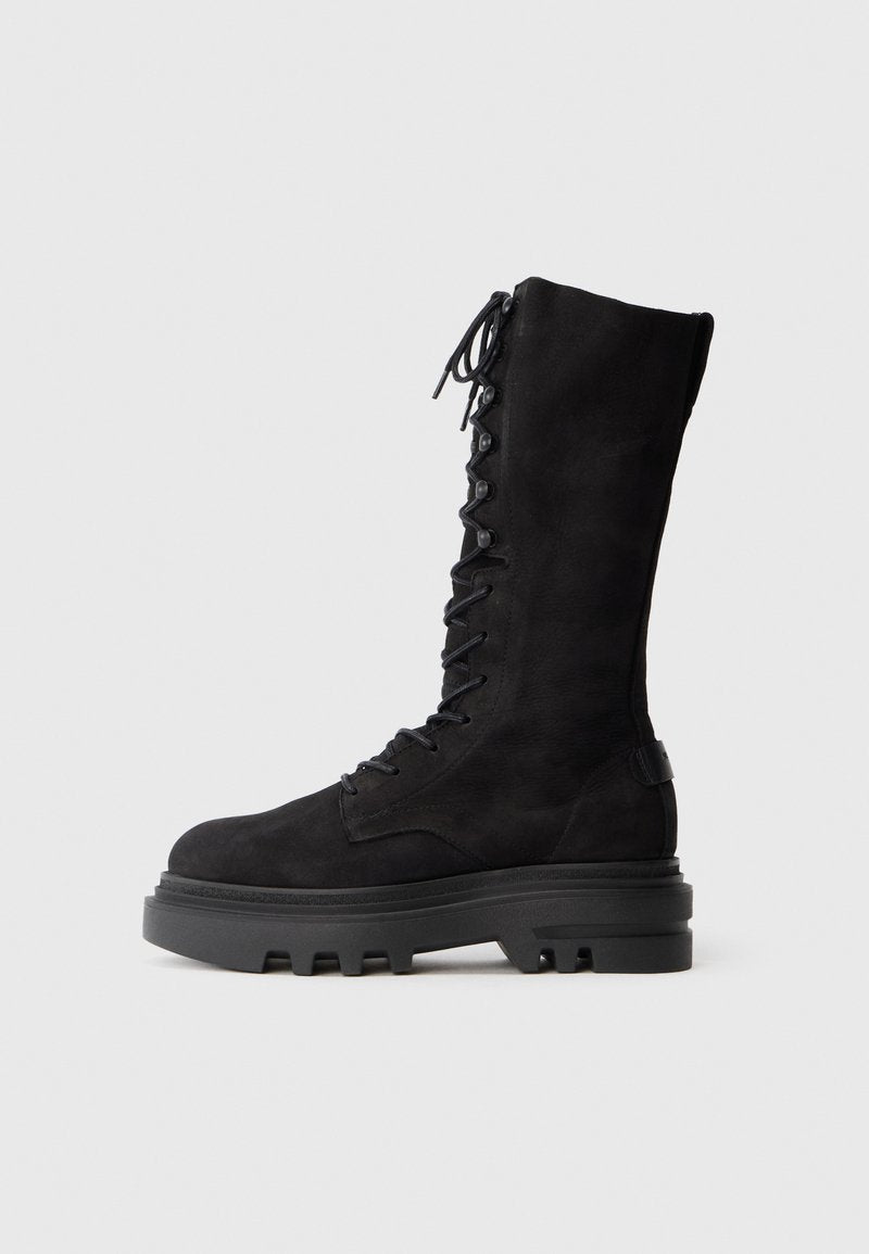 Schwarze knielange Schnürstiefel aus Wildleder, mit einer dicken Gummisohle mit einem robusten Profil und Metallösen für die Schnürsenkel.