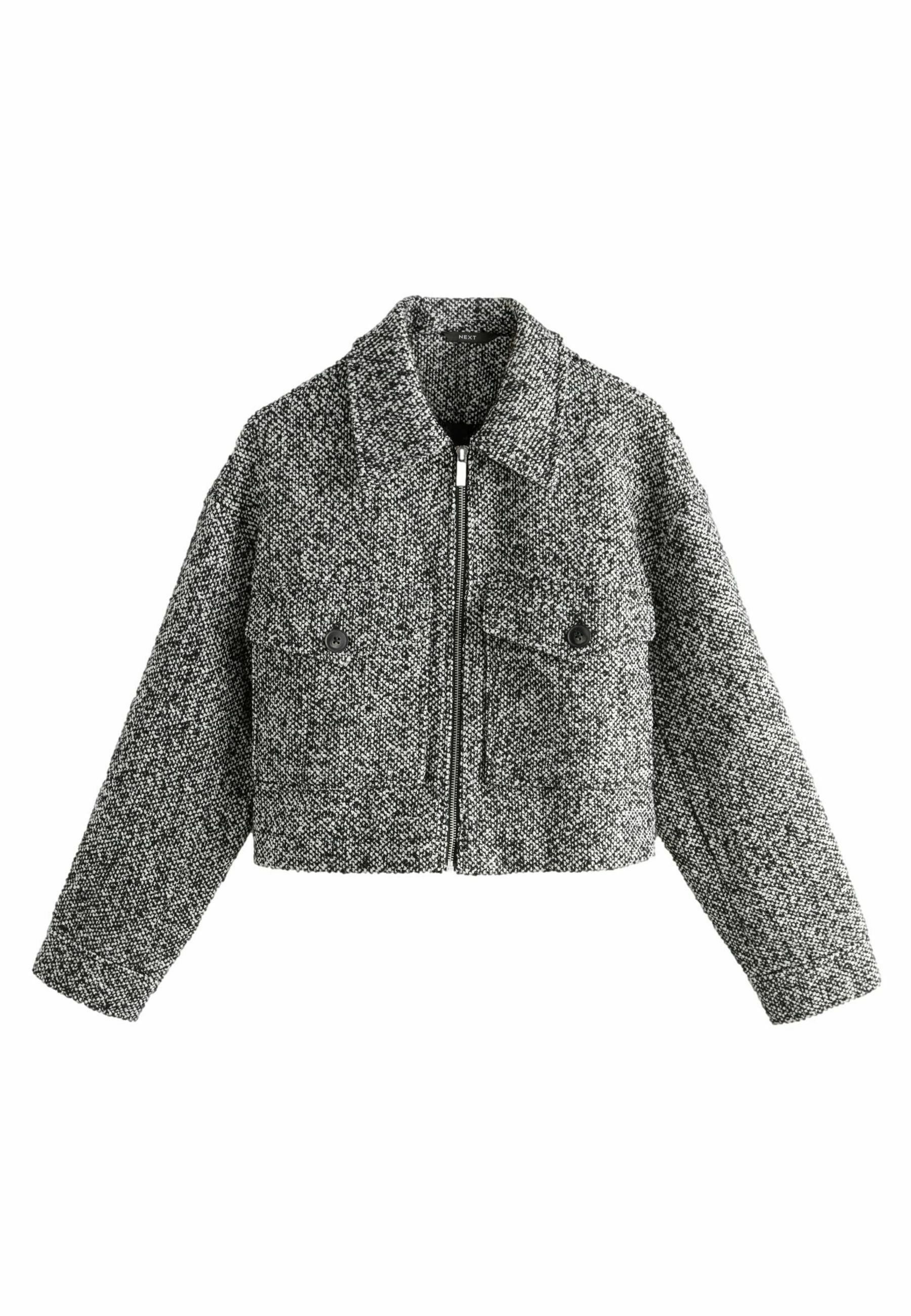 Gekürzte Jacke aus schwarz-weißer Tweed. Verfügt über einen Reißverschluss vorne, große Klappen und zwei Fronttaschen mit runden Knöpfen. Texturiert.