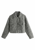 Gekürzte Jacke aus schwarz-weißer Tweed. Verfügt über einen Reißverschluss vorne, große Klappen und zwei Fronttaschen mit runden Knöpfen. Texturiert.