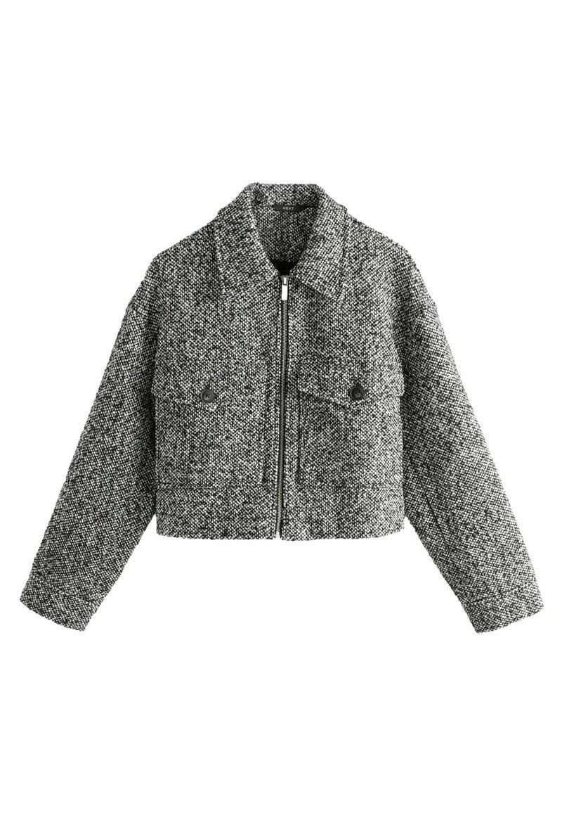 Gekürzte Jacke aus schwarz-weißer Tweed. Verfügt über einen Reißverschluss vorne, große Klappen und zwei Fronttaschen mit runden Knöpfen. Texturiert.