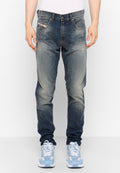 Blaue Denim-Jeans mit einem ausgewaschenen Effekt und leichten Abnutzungen. Verfügt über fünf Taschen und einen Knopfverschluss. Kombiniert mit hellblauen Sneakern.