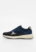 Niedriger Sneaker mit marineblauen, schwarzen und grauen Einsätzen, Schnürverschluss und cremefarbener dicker Sohle auf weißem Hintergrund.