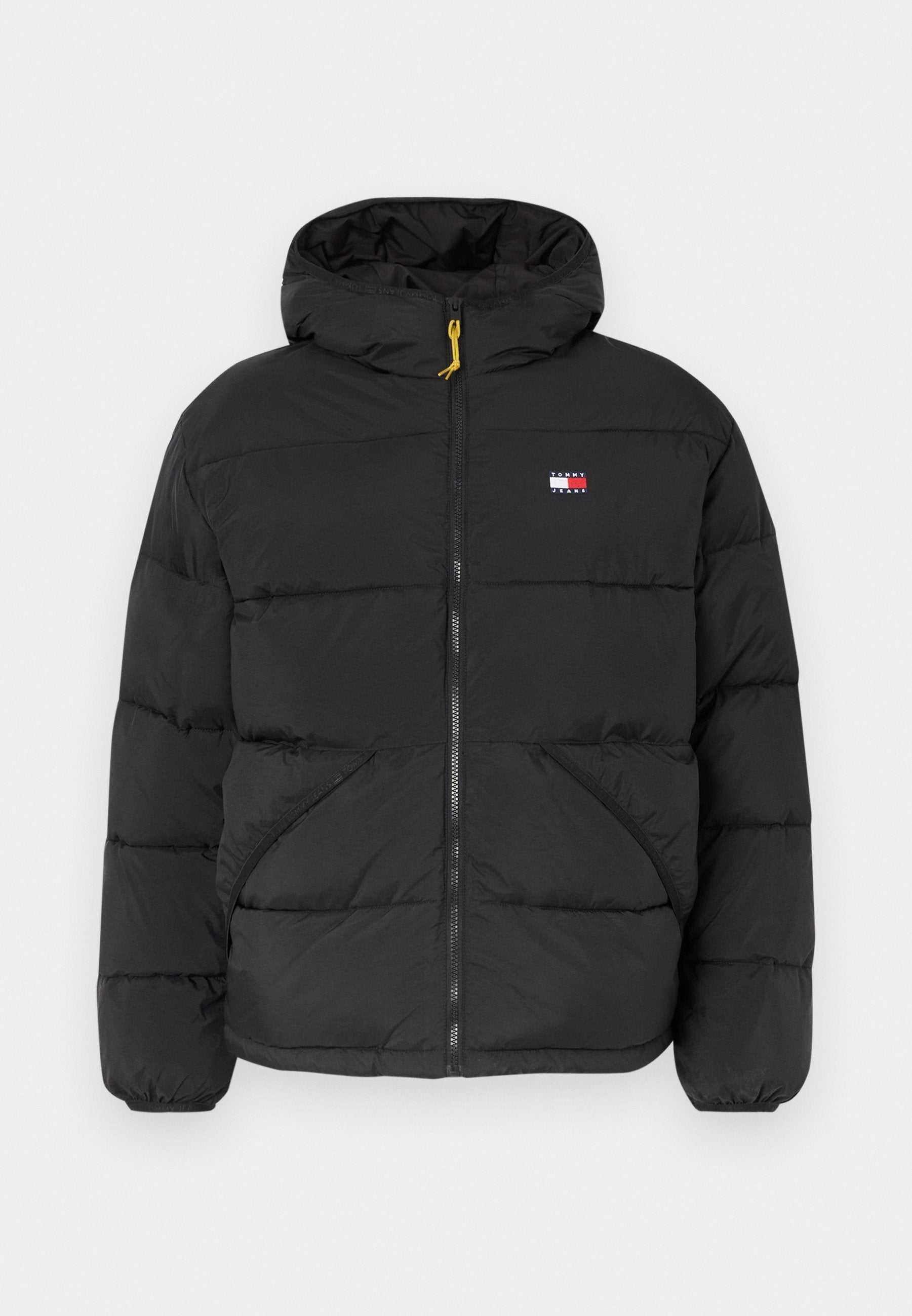 Schwarze, isolierte Pufferjacke mit Kapuze, mit Reißverschluss, zwei Seitentaschen und einem kleinen Logoschild auf der Brust. Gelber Reißverschlussakzent.