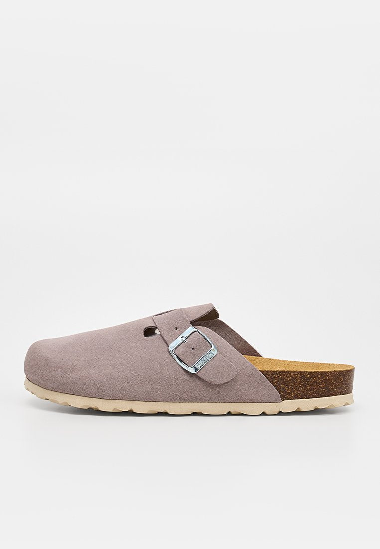 Hellbrauner Wildleder-Slipper im Clog-Stil mit silberner verstellbarer Schnalle, Kork-Fußbett und hellbeiger strukturierter Gummisohle, seitlich gezeigt.