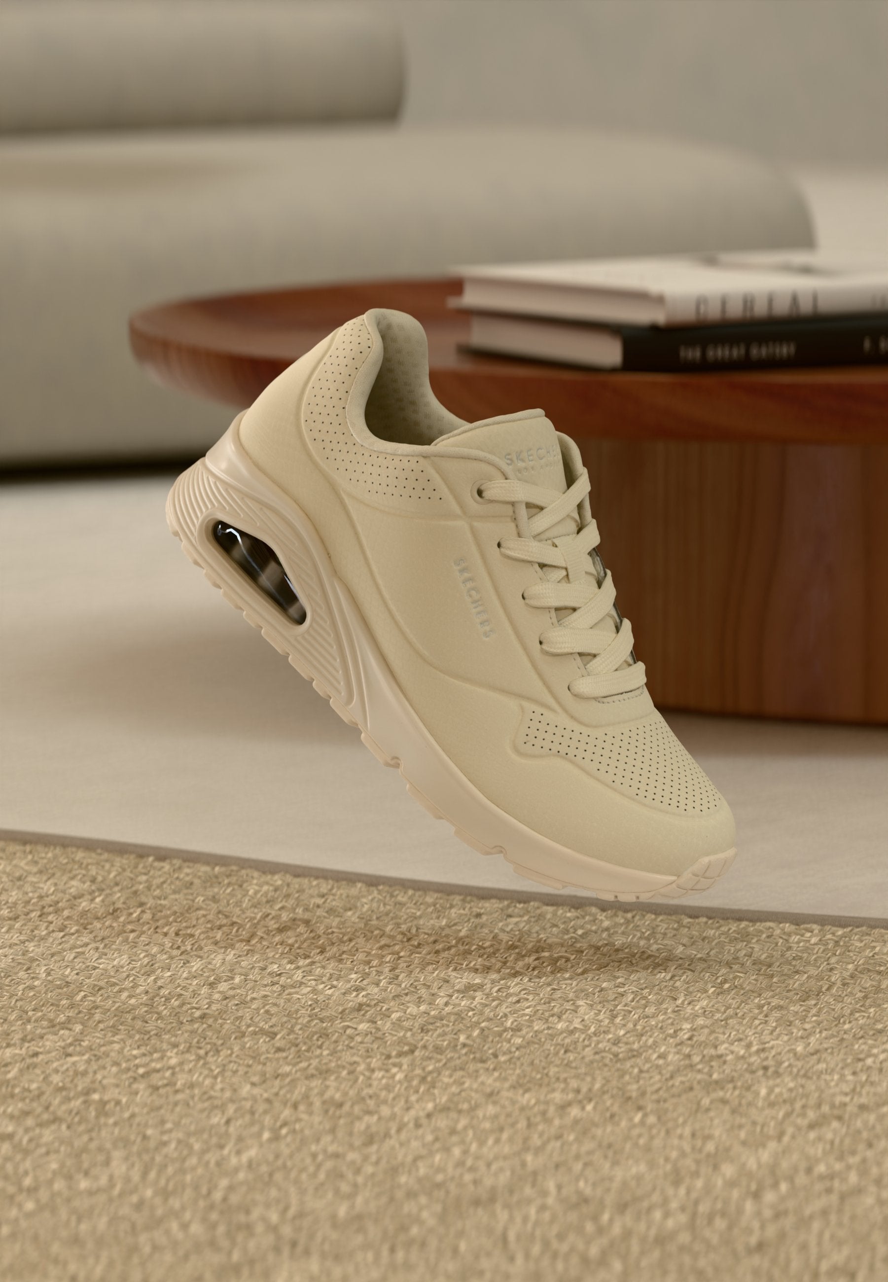 Beiger Sneaker mit Mesh-Obermaterial, Schnürverschluss und perforierten Details. Verfügt über eine sichtbare Air-Dämpfungseinheit in der Sohle.