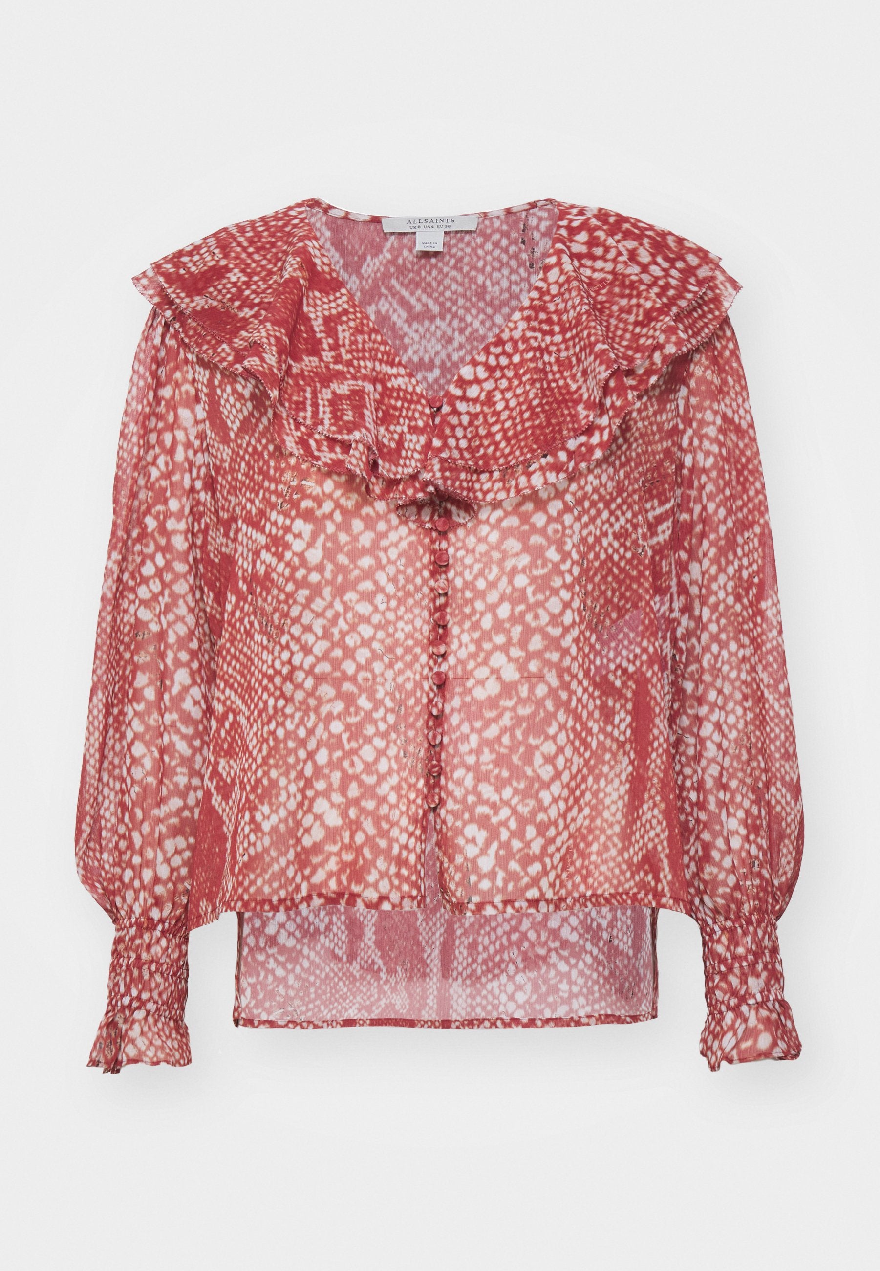 Rote durchsichtige Bluse mit einem rüschengeschmückten Kragen, langen Puffärmeln mit elastischen Bündchen und einer Knopfleiste. Mit hellen und dunklen Punkten gemustert.