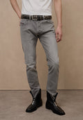 Graue Jeans mit schmaler Passform, strukturiertem Stoff und leichtem Used-Look. Kombiniert mit schwarzen Reißverschluss-Stiefeletten und einem schwarzen Nieten-Gürtel.