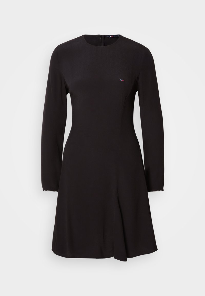Schwarzes langärmliges Kleid mit rundem Ausschnitt und leicht ausgestellter Form. Verfügt über ein dezentes Logo auf der Brust und strukturierte Stoffakzente an den Ärmeln.