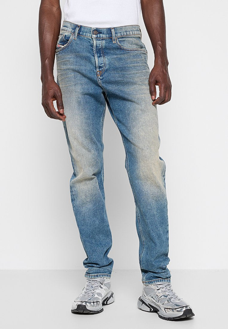 Hellblaue Jeans aus Denim mit einem verblassten Finish. Klassisches Fünf-Taschen-Design, Knopfverschluss und gerader Schnitt. Getragen mit silbernen Sneakers.