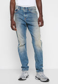 Hellblaue Jeans aus Denim mit einem verblassten Finish. Klassisches Fünf-Taschen-Design, Knopfverschluss und gerader Schnitt. Getragen mit silbernen Sneakers.