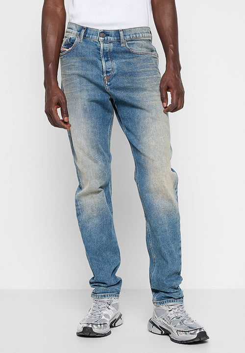 Hellblaue Jeans aus Denim mit einem verblassten Finish. Klassisches Fünf-Taschen-Design, Knopfverschluss und gerader Schnitt. Getragen mit silbernen Sneakers.