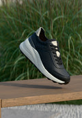 Schwarzer Ledersneaker mit hellgrauen Akzenten, glatter Textur, rundem Zehenbereich, Schnürdesign und kleinen Nieten-Details an der Seite.